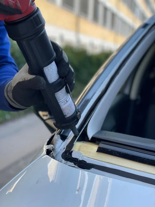 Technician applying adhesive before windshield installation