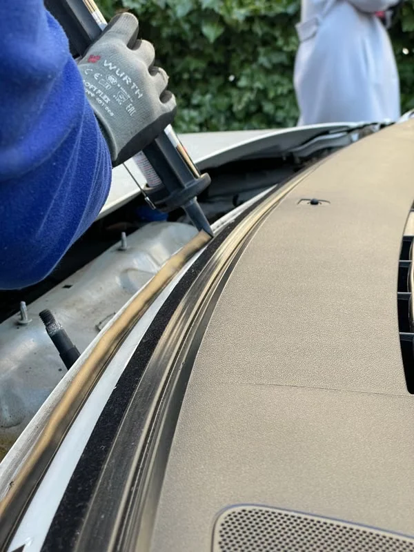 Gloved technician carefully preparing the windshield frame